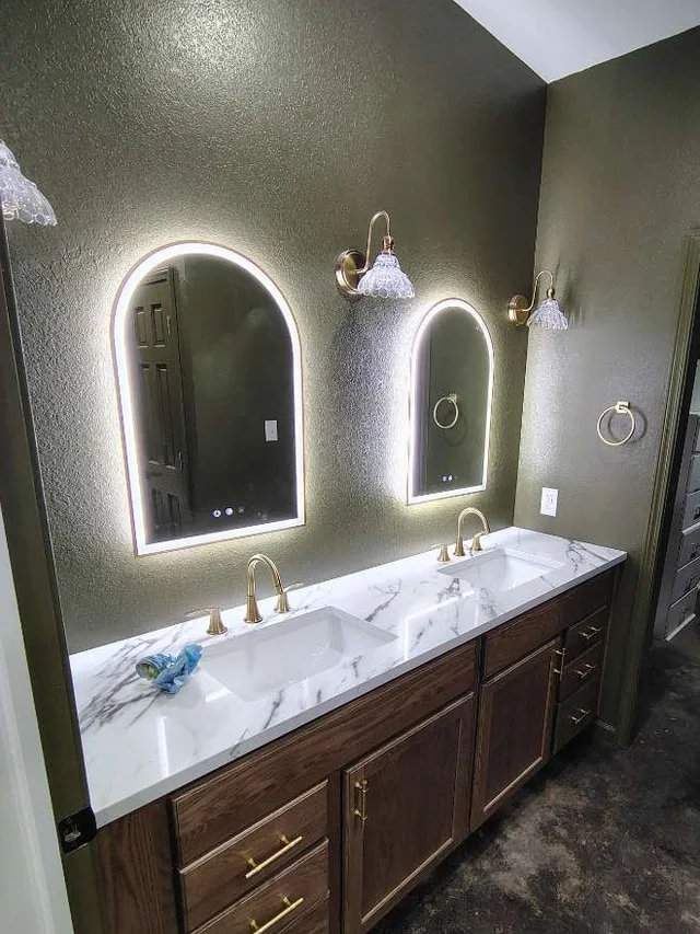 Double vanity with arched lighted mirrors, brass fixtures and stone top in the same Grove, Oklahoma custom home bathroom